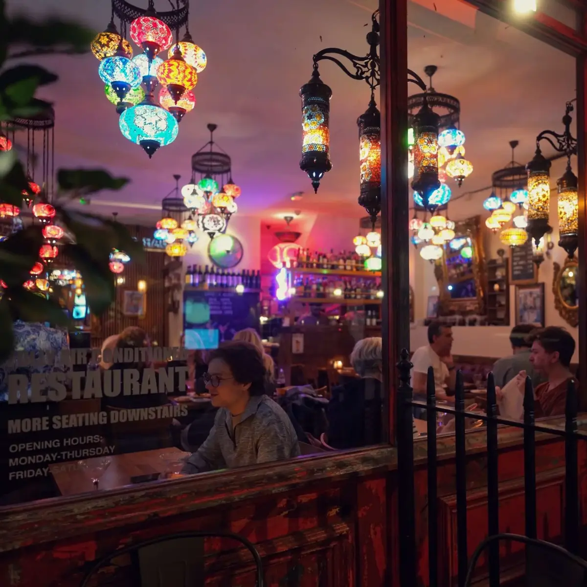 Turkish lamps glowing in the window of Bistro 1 on Frith Street at night